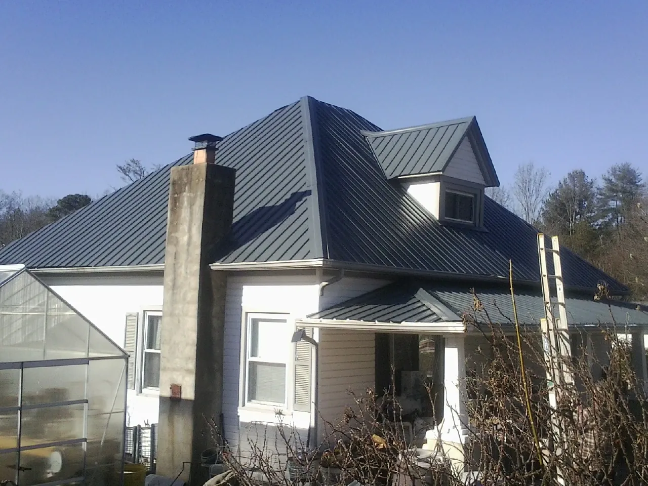 Dark blue standing seam metal roof on a white farmhouse with dormer — Slate & Tile Roof Repair by Roofing Brothers in Rembert