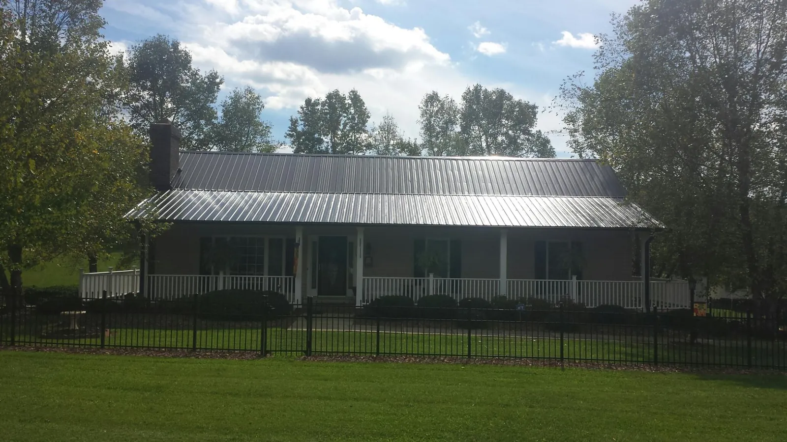 Gray metal roof on a brick ranch with a full width front porch — Gutter Guard Installation work by our crew in Rembert