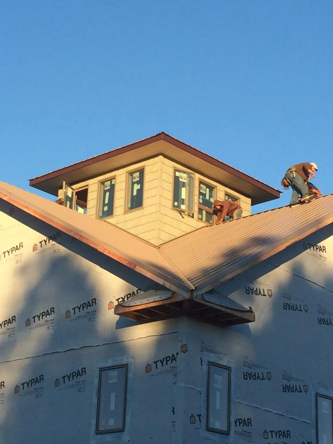 Roofers working around a rooftop cupola on a new metal roof at sunset — Roof Waterproofing in Rembert by Roofing Brothers